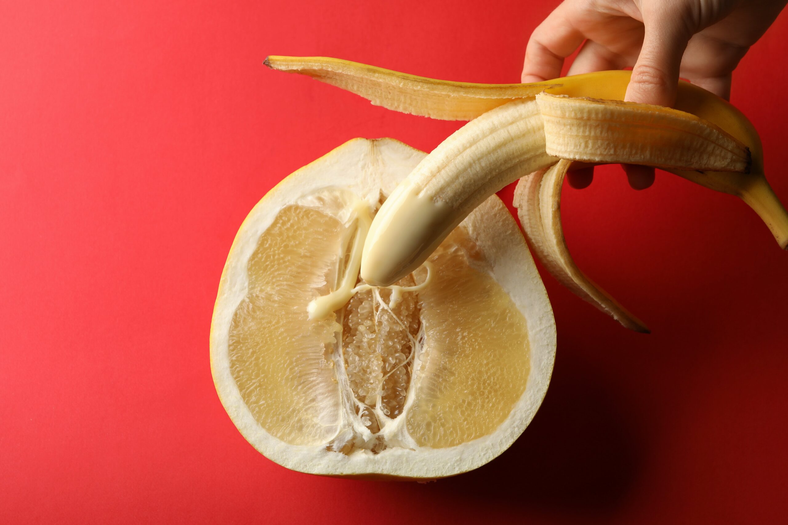 female-hand-hold-banana-with-condensed-milk-on-pomgranate